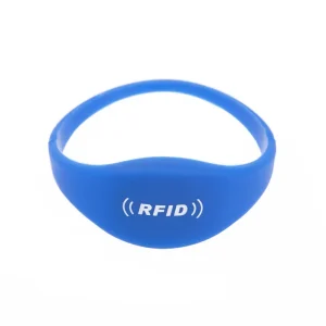 Pulsera con etiqueta RFID azul adornada con un logotipo RFID blanco y un ícono de señal en el frente, sobre un fondo blanco. Este elegante accesorio se integra perfectamente con otras pulseras con etiquetas RFID., ofreciendo estilo y seguridad.